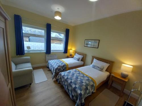 卡蘭德的住宿－Stunning Village Centre Holiday Home，一间卧室设有两张床、一把椅子和一个窗户。