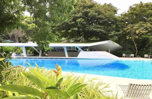 Maribago的住宿－TAMBULI SEASIDE LIVING STAYCATION，一座带房子和树木的蓝色游泳池