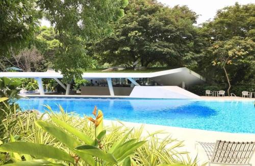 a blue swimming pool with a house and trees at CEBU's Best Staycation at Tambuli Seaside Living Tower C in Maribago