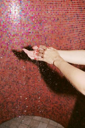 a person washing their hand in a shower at SOULSISTERS' Hotel 4 Sterne Superior in Kaprun