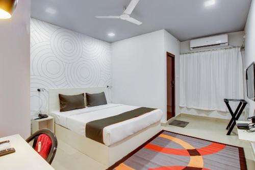 - une chambre blanche avec un lit, un bureau et un tapis dans l'établissement Collection O Airport View Guest House Airport Road, à Soalkuchi
