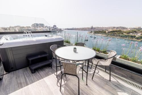 a balcony with a bath tub and tables and chairs at The Londoner Hotel Sliema in Sliema