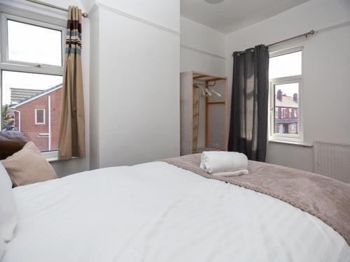 Cama blanca en habitación con 2 ventanas en Pass the Keys Spacious home near City Centre en Mánchester