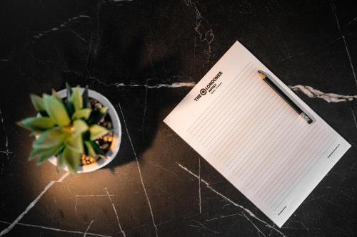 a pen and a notebook next to a plant and a bowl at The Londoner Hotel Sliema in Sliema