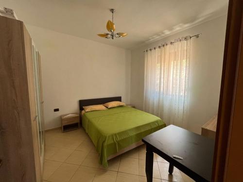 a bedroom with a green bed and a table at Laert's Home in Sarandë