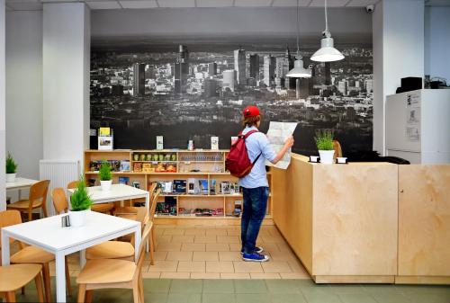a person standing at a counter in a restaurant at Warsaw Hostel Centrum Private Rooms & Dorms in Warsaw