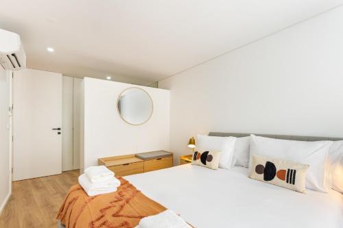 a white bedroom with a large bed and a mirror at Dom Miguel Ap City Center By Sé Apartamentos in Braga
