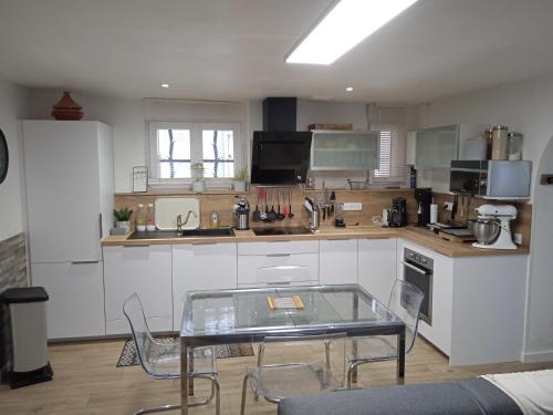 une cuisine avec une table en verre et des chaises. dans l'établissement MAISON CENTRE VILLAGE PROCHE MER, à Saint-Cyr-sur-Mer
