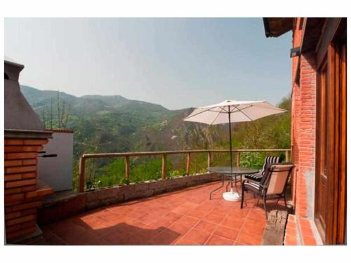 eine Terrasse mit einem Tisch und einem Sonnenschirm in der Unterkunft El Ablanu Senda del Oso in Proaza