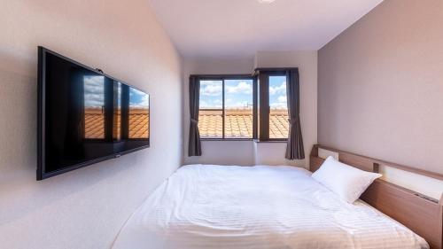 een slaapkamer met een bed en een flatscreen-tv bij FLY CAT HOTEL in Minokamo