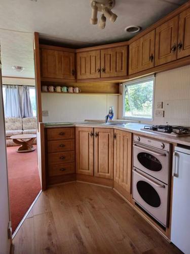 uma cozinha com armários de madeira e um forno de fogão branco em Y Golygfa em Sarnau