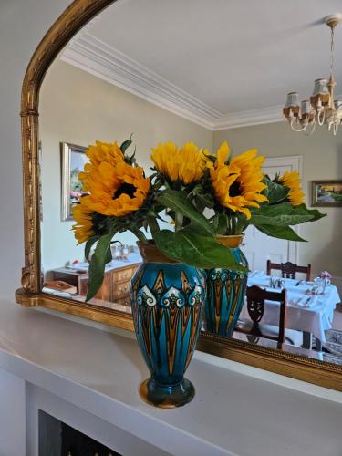 a vase filled with sunflowers in front of a mirror at Craggan in Ballater