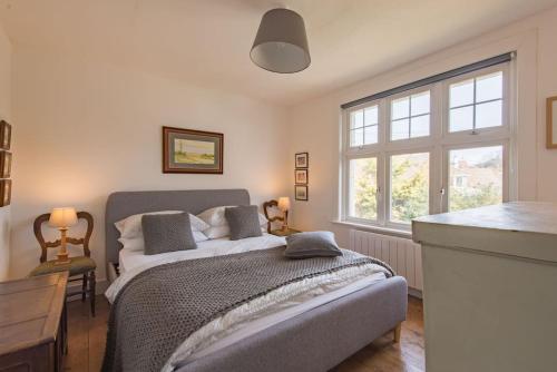 a bedroom with a bed and a desk and windows at Poppy Cottage in Kingsdown