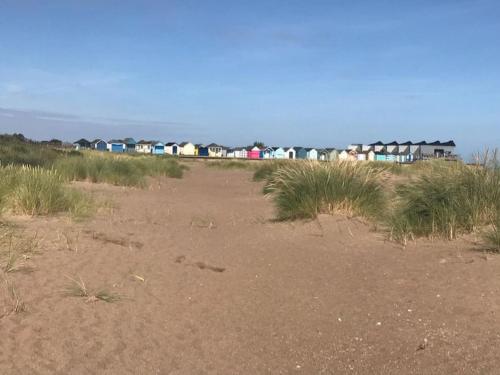 a row of houses on a beach with grass at El Sea House in Chapel Saint Leonards