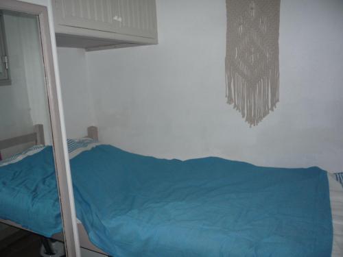une chambre avec un lit bleu et un miroir dans l'établissement Coquet appartement à quelques pas de la mer, au Grau-dʼAgde