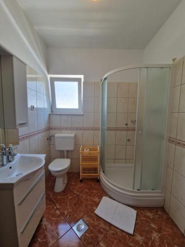 een badkamer met een douche, een toilet en een wastafel bij Apartments Šime in Šibenik