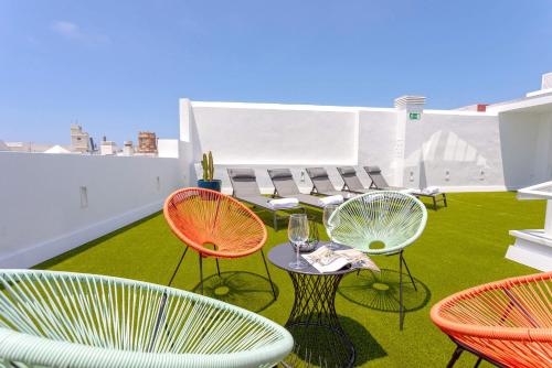 a patio with chairs and tables on a roof at Genteel Home Catedral in Cádiz