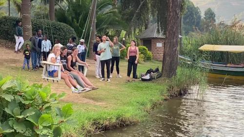 a group of people sitting next to a body of water at Nyamunyonyi Lake Resort in Kabale