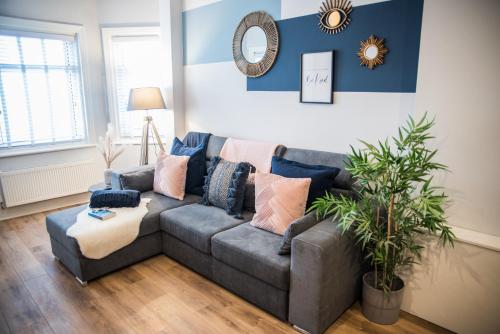 a living room with a gray couch with pillows at Blackpool Abode - Beach Suite Apartment in Blackpool