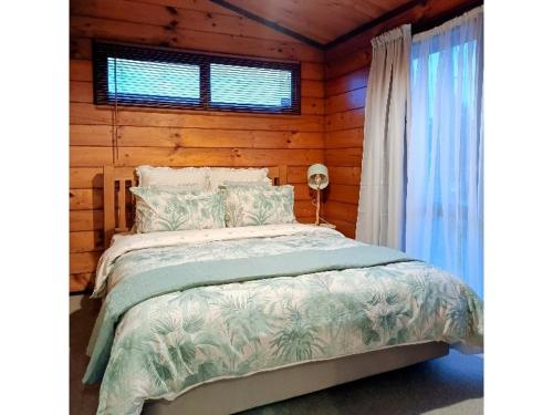 um quarto com uma cama num chalé de madeira em Cosy in central Rotorua em Rotorua