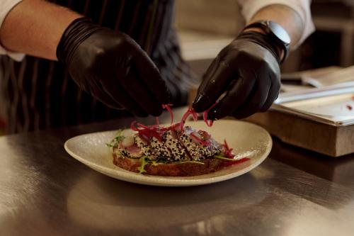 a person in black gloves preparing a plate of food at SOULSISTERS' Hotel 4 Sterne Superior in Kaprun