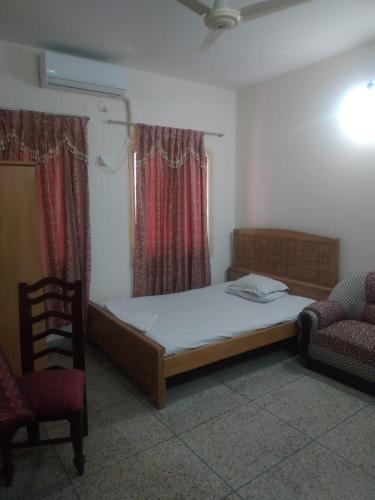 a bedroom with a bed and a chair and a window at Hotel Western Planet in Dhaka