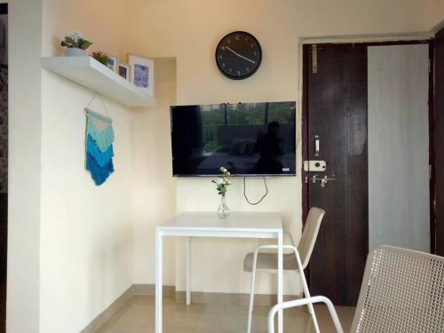 une table, deux chaises et une horloge sur un mur dans l'établissement 7 - Studio Velankanni Heights, Behaind Nanavati Hospital, Vile Parle by Connekt Homes, à Mumbai