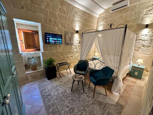 a bedroom with a bed and chairs in a room at Ta' Ġilarda Boutique Living in Birbuba