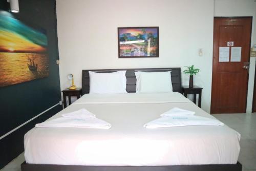 a bedroom with a large white bed with two towels on it at Sunshine Hotel in Hua Hin