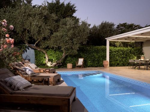 a swimming pool in a backyard with a table and chairs at Jasmine Suites with Private Pool in Tsilivi