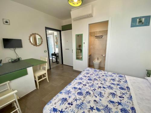 1 dormitorio con cama, escritorio y baño en Casetta al mare, en Isola Rossa