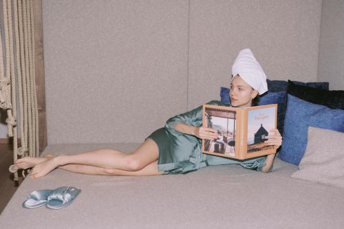 a young girl laying on a bed reading a book at SOULSISTERS' Hotel 4 Sterne Superior in Kaprun