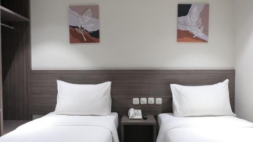 two beds in a hotel room with white sheets at Lun Hotel Manado in Manado