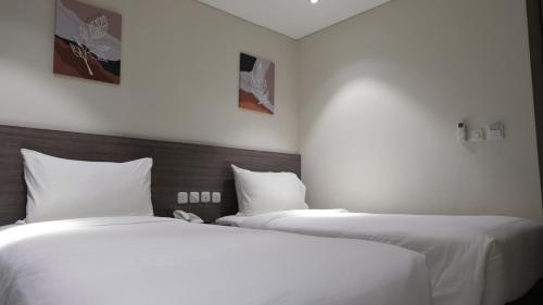 two beds in a hotel room with white sheets at Lun Hotel Manado in Manado