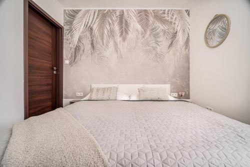 - une chambre avec un grand lit blanc orné d'une fresque murale en palmier dans l'établissement Apartments By Pyramid - Michal, à Bratislava