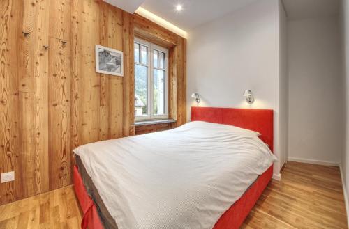 - une chambre avec un lit rouge et des murs en bois dans l'établissement Apartment Bonatti 201, à Chamonix-Mont-Blanc