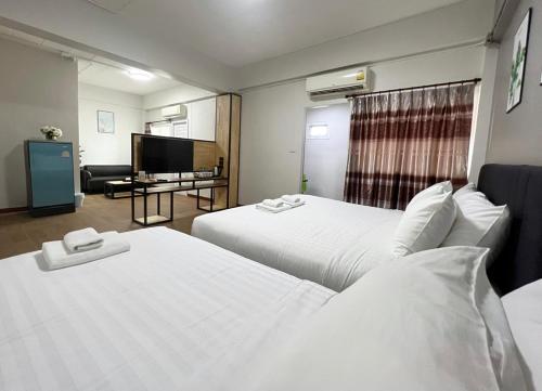 a hotel room with two beds and a flat screen tv at Golden Nest Hotel Suvarnabhumi in Bangkok