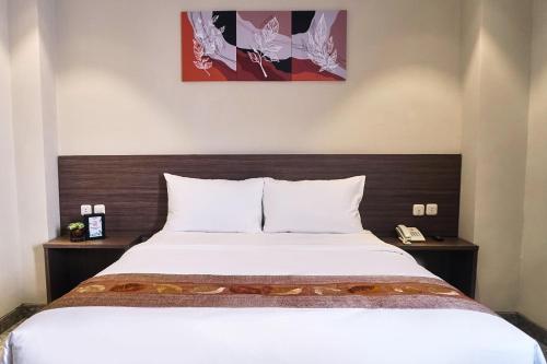 una camera da letto con un grande letto con lenzuola bianche di Lun Hotel Manado a Manado