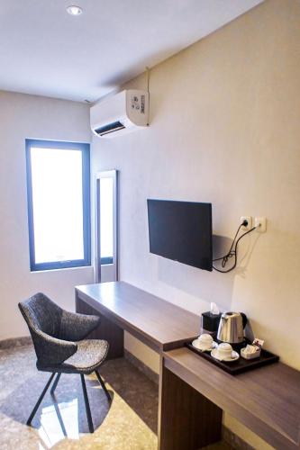 a room with a desk and a chair and a television at Lun Hotel Manado in Manado