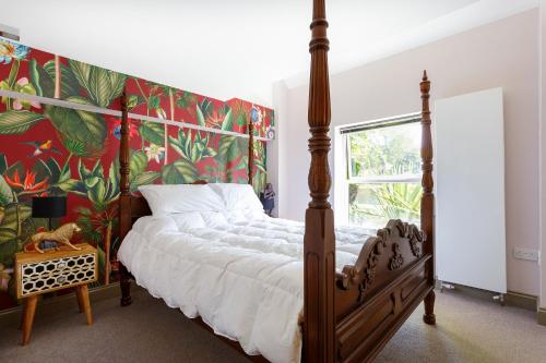 1 dormitorio con cama con dosel y papel pintado tropical en Eel Pie Retreat, en Twickenham