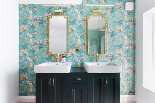 baño con 2 lavabos y papel pintado con motivos florales en Eel Pie Retreat, en Twickenham