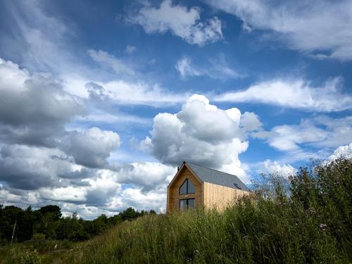 a small house on a hill with a cloudy sky at Tarset Tor - Bothy Cabin 4 in Hexham