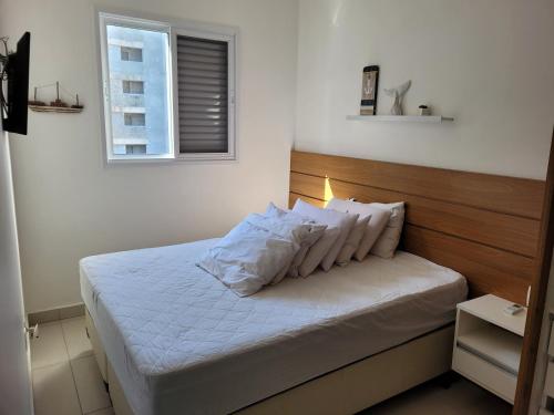 een slaapkamer met een bed met witte lakens en kussens bij Ubatuba - Praia das Toninhas in Ubatuba