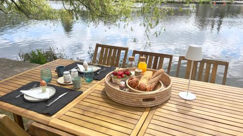 a picnic table with a basket of food on a table by the water at Pieds dans l'eau Private Wellness Bordure de Meuse in Lustin