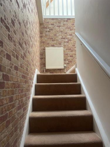a staircase with a brick wall and a white radiator at Beach House 3 Bed Penthouse Apartment in Southport