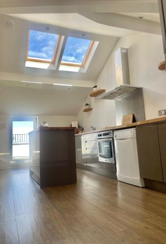 a large kitchen with white appliances and a ceiling with skylights at Beach House 3 Bed Penthouse Apartment in Southport