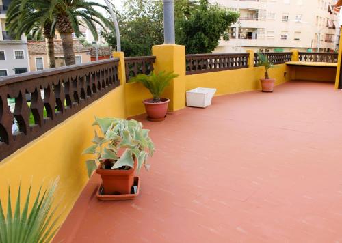 a balcony with potted plants on a yellow wall at Vacaciones tierra y mar Casa en el centro con patio y terraza in El Campello