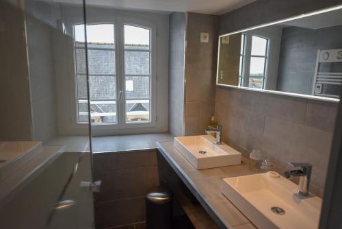 a bathroom with two sinks and a mirror at Les Remparts de Dinan . f3 intramuros. avec wifi in Dinan