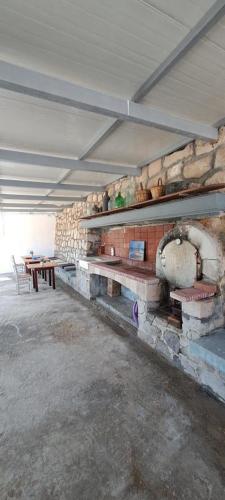 a room with a stone fireplace with a wooden table at AmatoNostro in Mandrakia