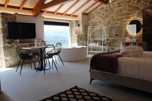 een slaapkamer met een bed, een tafel en een bad bij Apartamentos Villa Maceira in Covelo